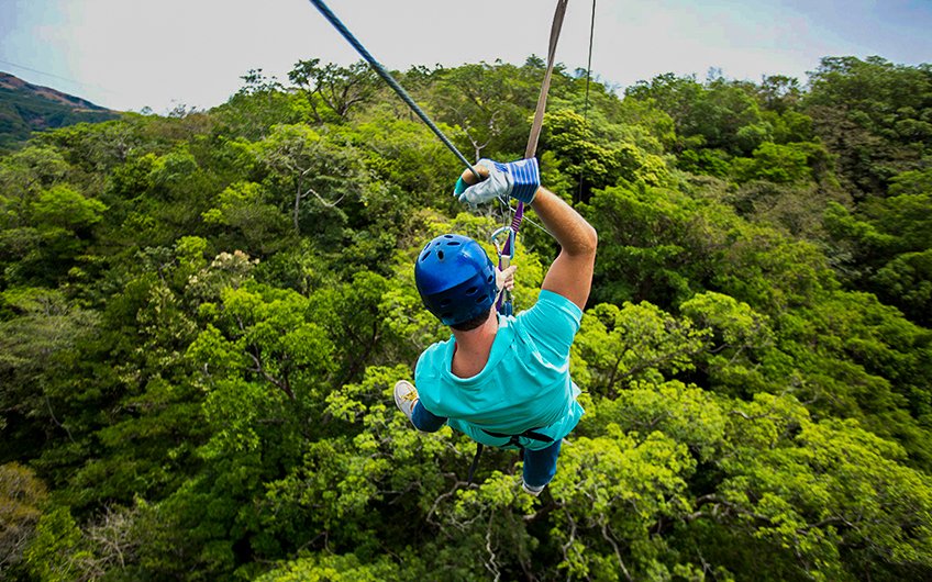 Persona disfrutando de una emocionante aventura de tirolesa (canopy) sobre la densa selva de Costa Rica.